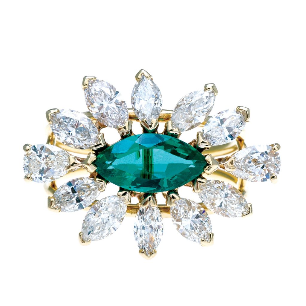 Yellow gold engagement ring centered with a marquise shaped emerald surrounded by pear and marquise shaped diamonds.