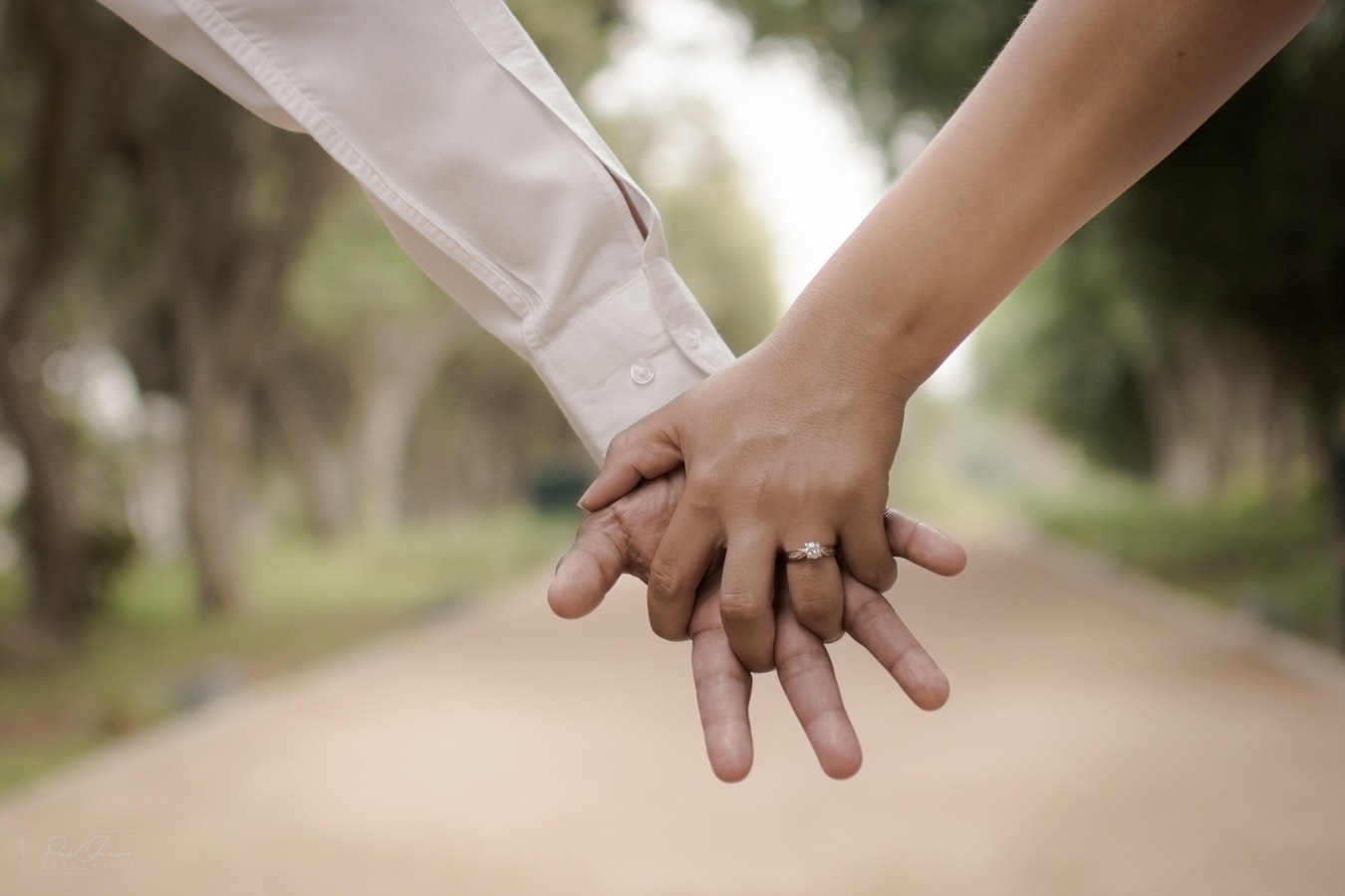 Bride and groom holding hands featuring her engagement ring.