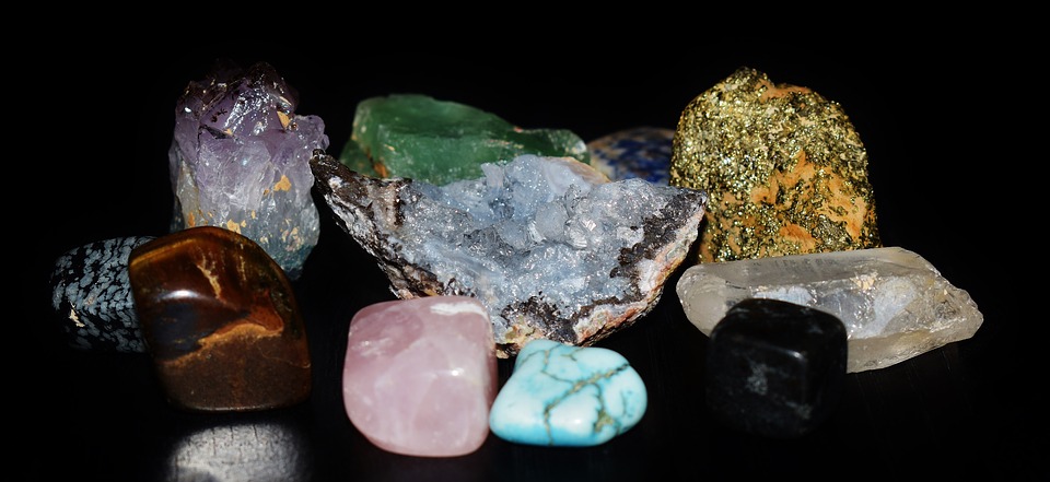 Various rough uncut gemstones on a black background.