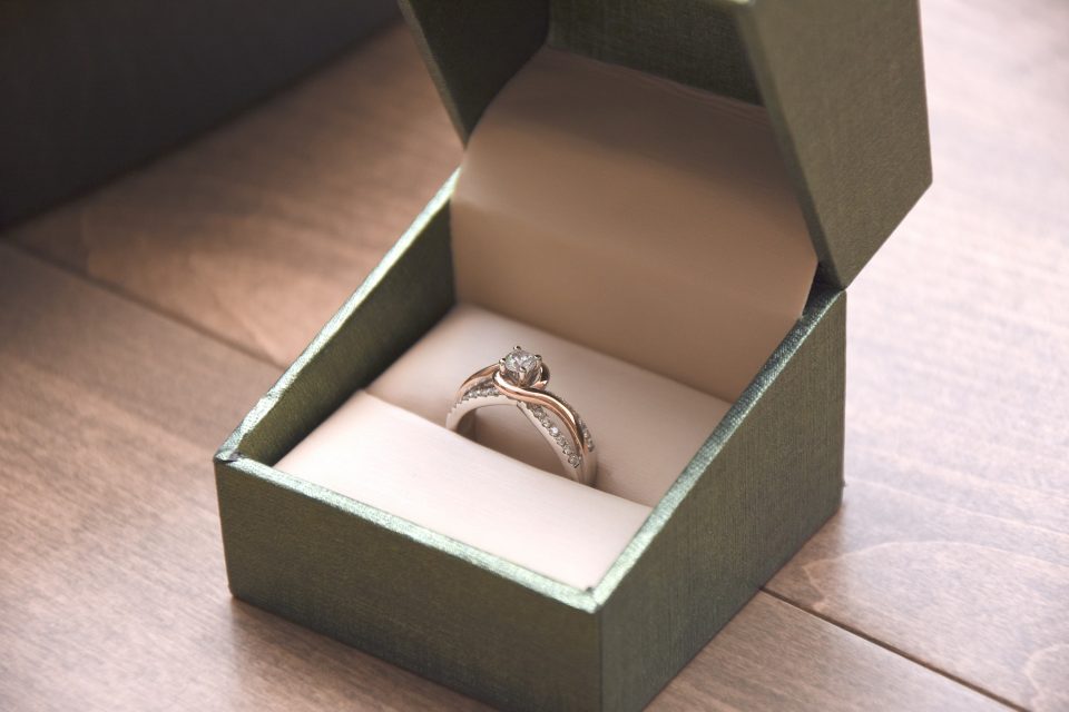 Yellow and white gold diamond engagement ring in a green ring box.