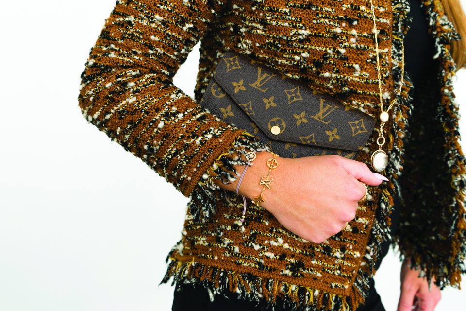 Woman clutching a vintage Louis Vuitton Monogram button wallet.