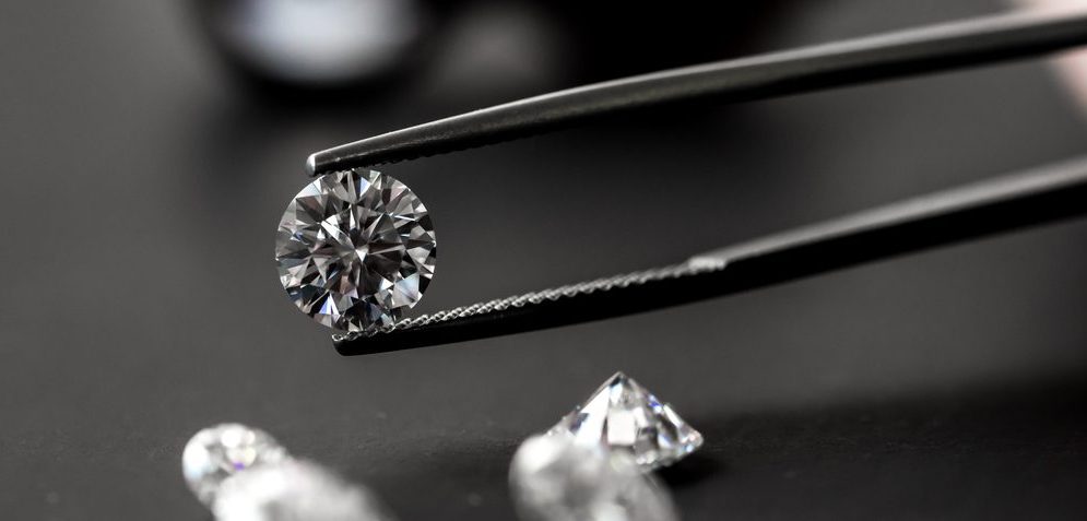 Tweezers holding a loose round cut diamond.