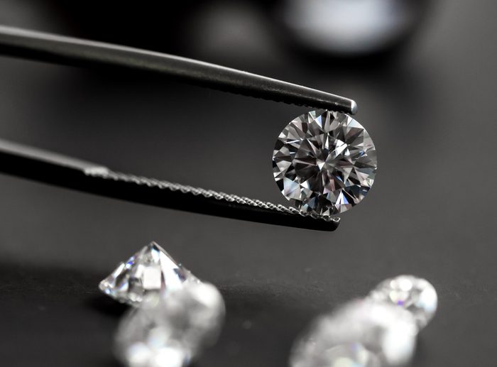 Tweezers holding a loose round cut diamond.