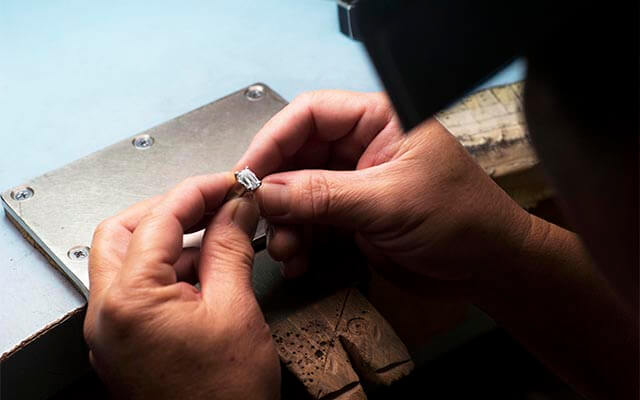 Jeweler working on engagement ring repair at their bench.