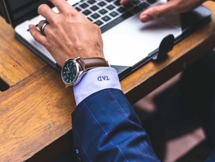 Man at laptop wearing luxury watch.