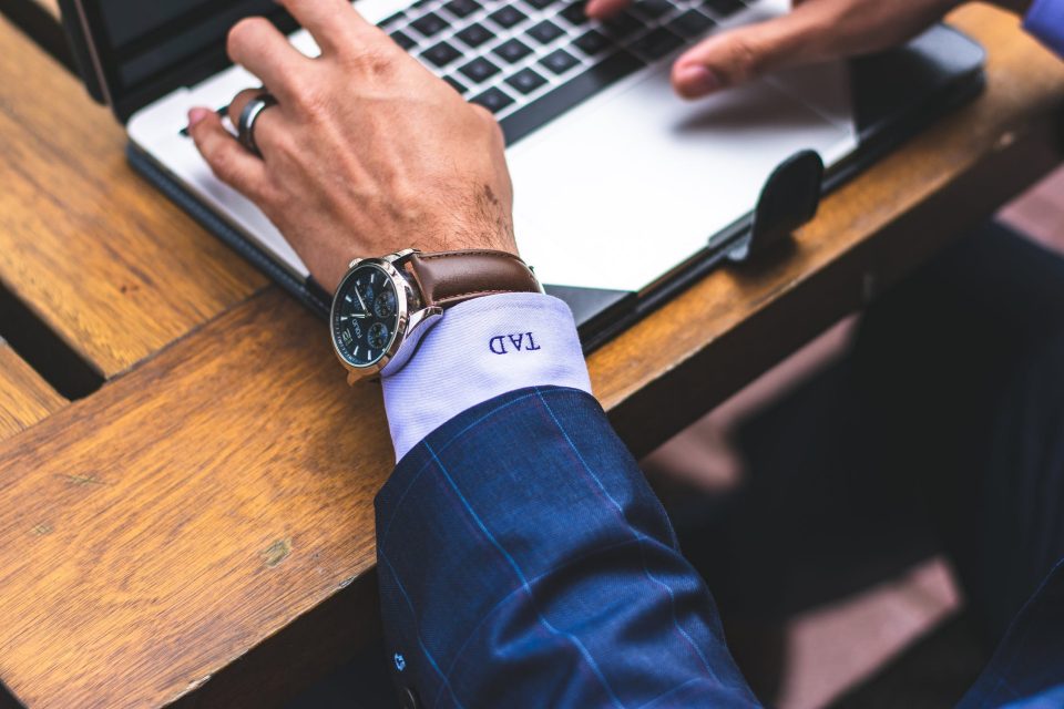 Man at laptop wearing luxury watch.