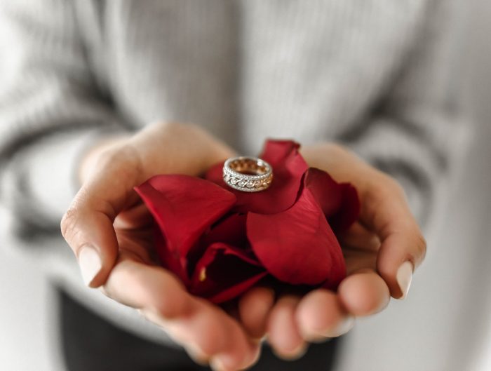 White gold diamond wedding band on red rose petals.