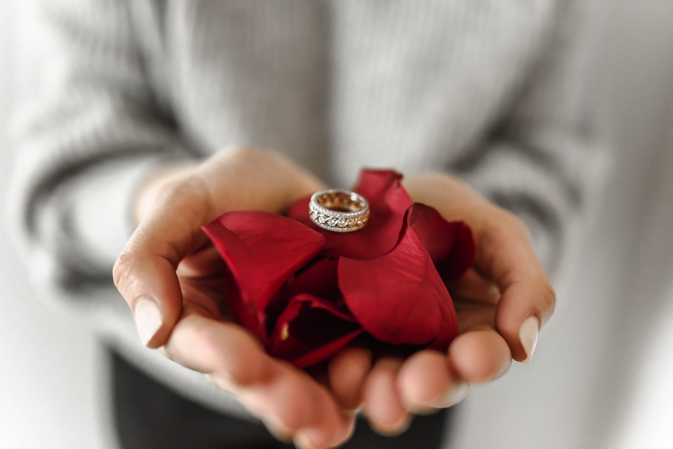 White gold diamond wedding band on red rose petals.