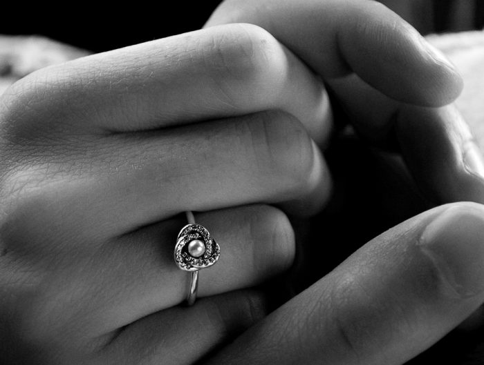 Couple holding hands showing off woman’s diamond engagement ring.