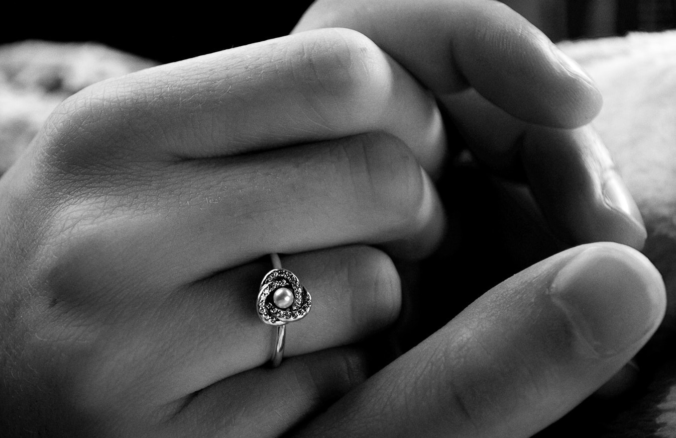 Couple holding hands showing off woman’s diamond engagement ring.