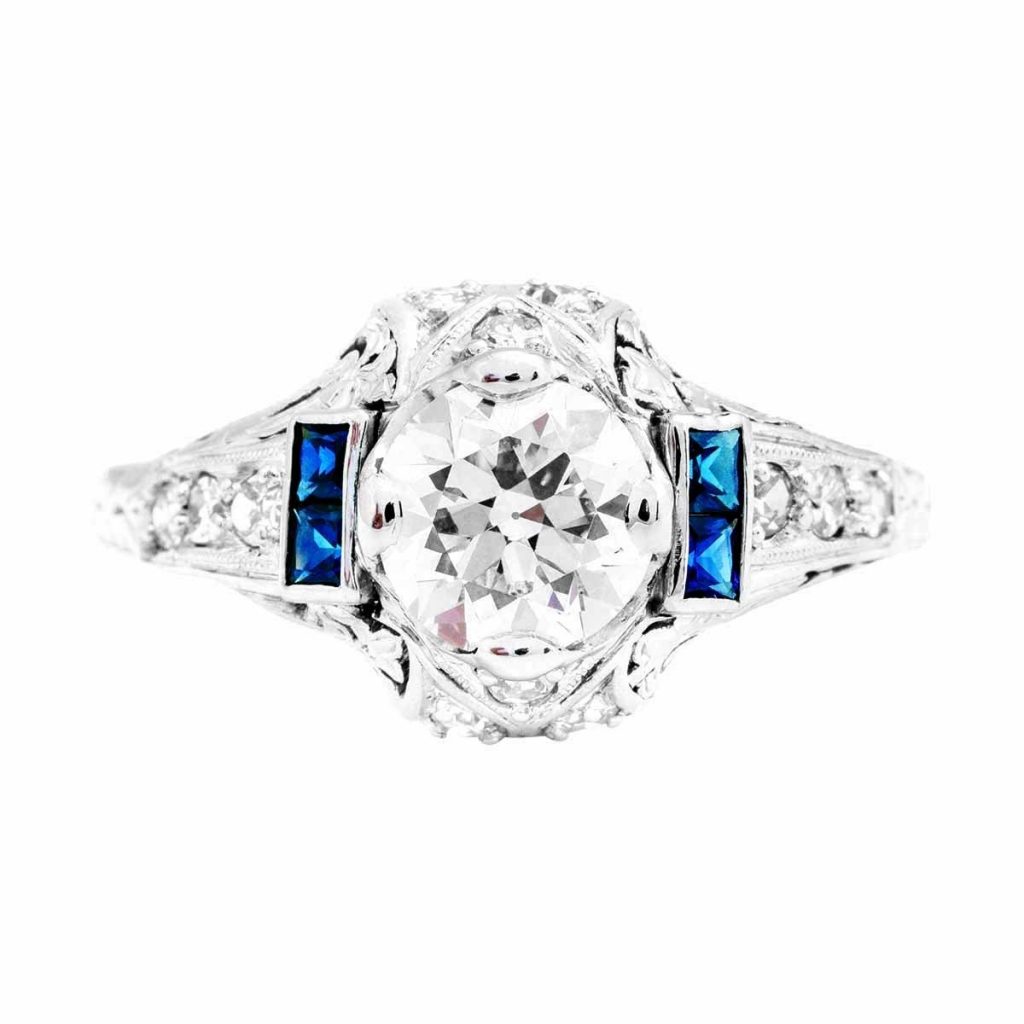White gold Art Deco diamond engagement ring surrounded by blue sapphires and diamonds.