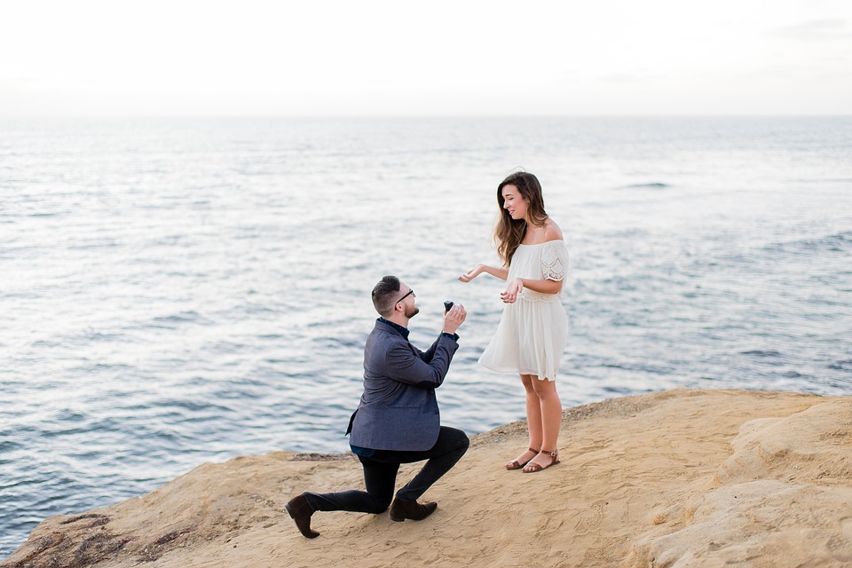 Man proposing to woman on cliff edge at the beach.