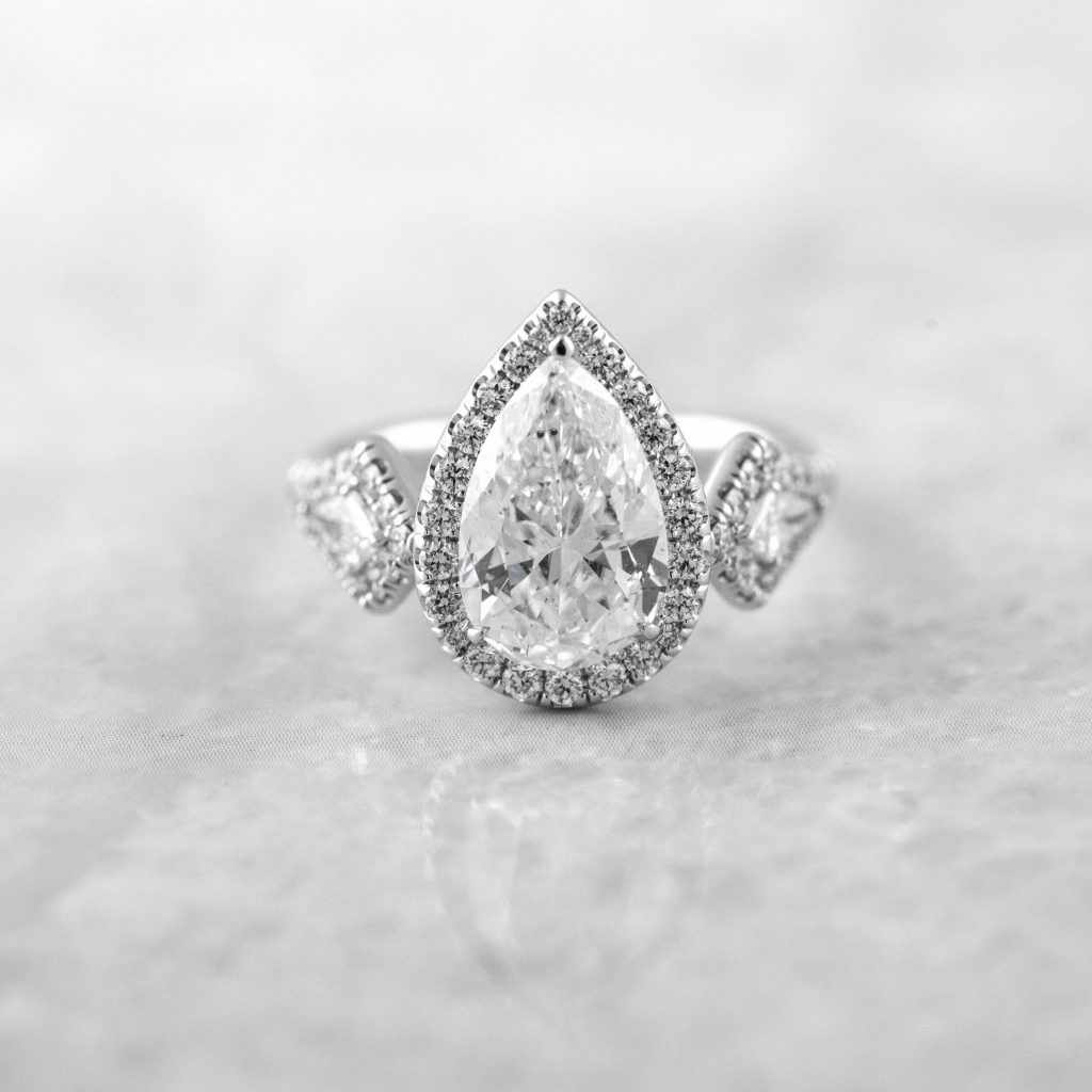 White gold diamond engagement ring with diamond halo and diamond side stones.