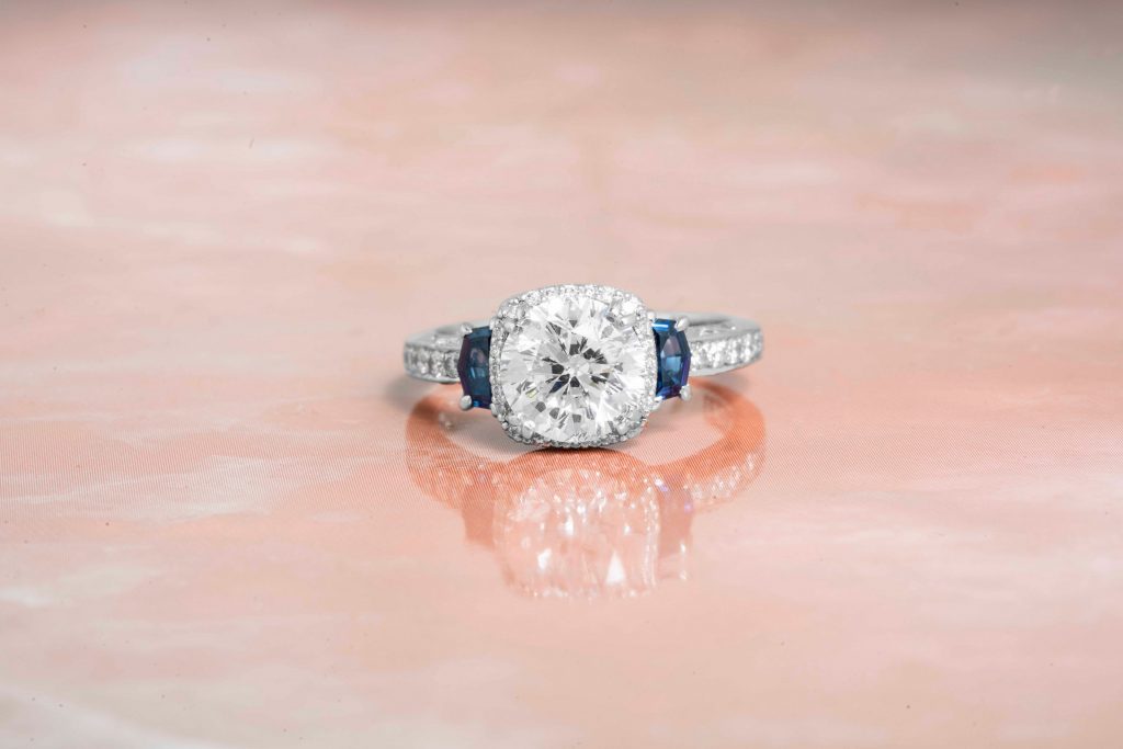 White gold diamond engagement ring with half-moon blue sapphire side stones and
diamonds in the band.