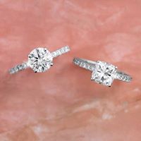 two white diamond engagement rings in a hand