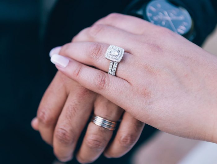 Bride and groom holding hands showing off her diamond wedding set and his white gold wedding band.