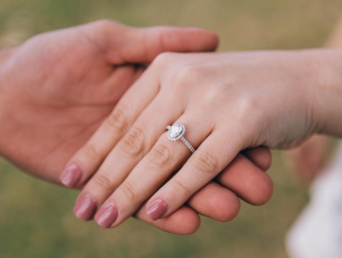 Man holding woman’s hand showing off her diamond engagement ring.