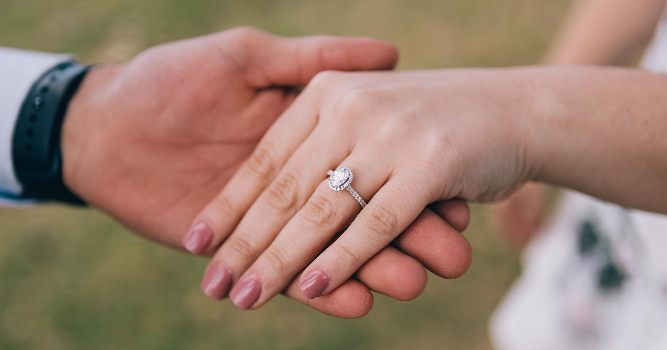 Man holding woman’s hand showing off her diamond engagement ring.