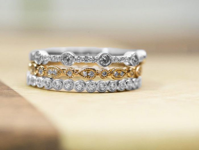 Yellow and white gold stackable diamond eternity rings on wooden table.