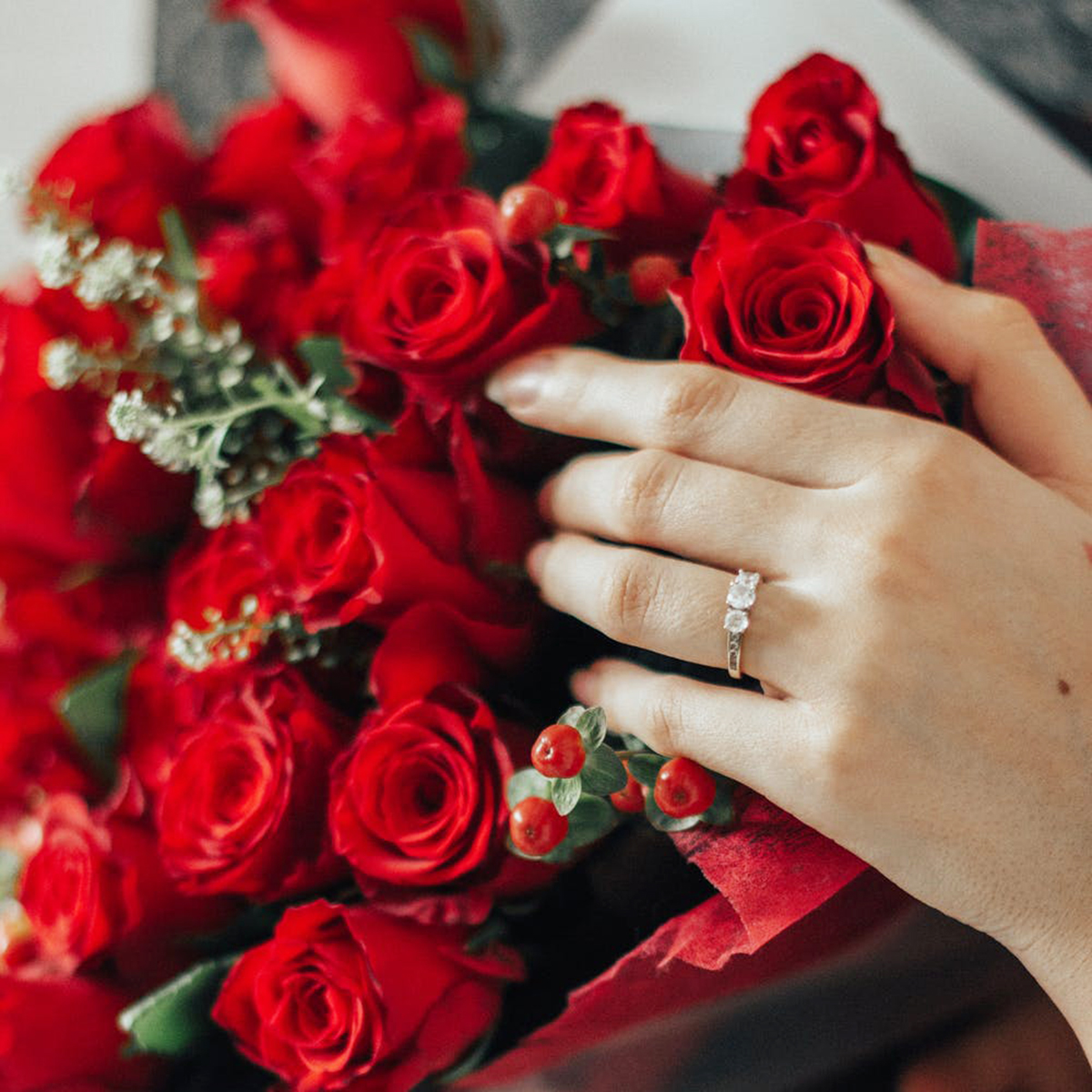 Woman holding a bouquet of red roses.