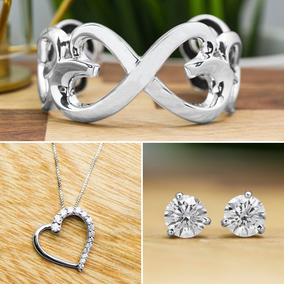 White gold open heart ring, white gold diamond open heart pendant, and white gold
diamond stud earrings on wooden table.