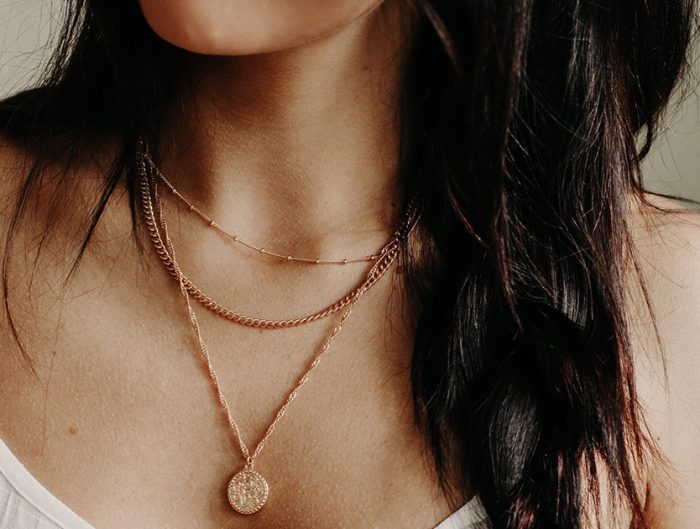 Woman wearing pendant necklace layered with two choker chains.