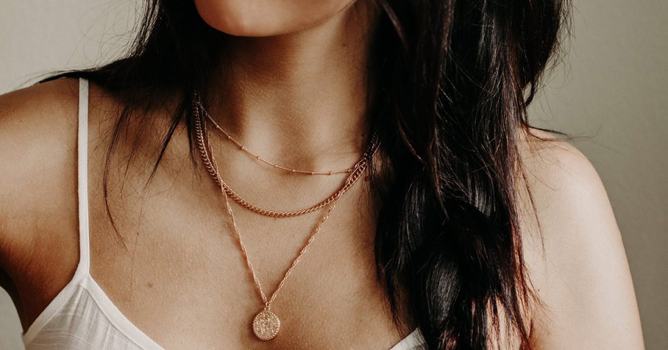 Woman wearing pendant necklace layered with two choker chains.