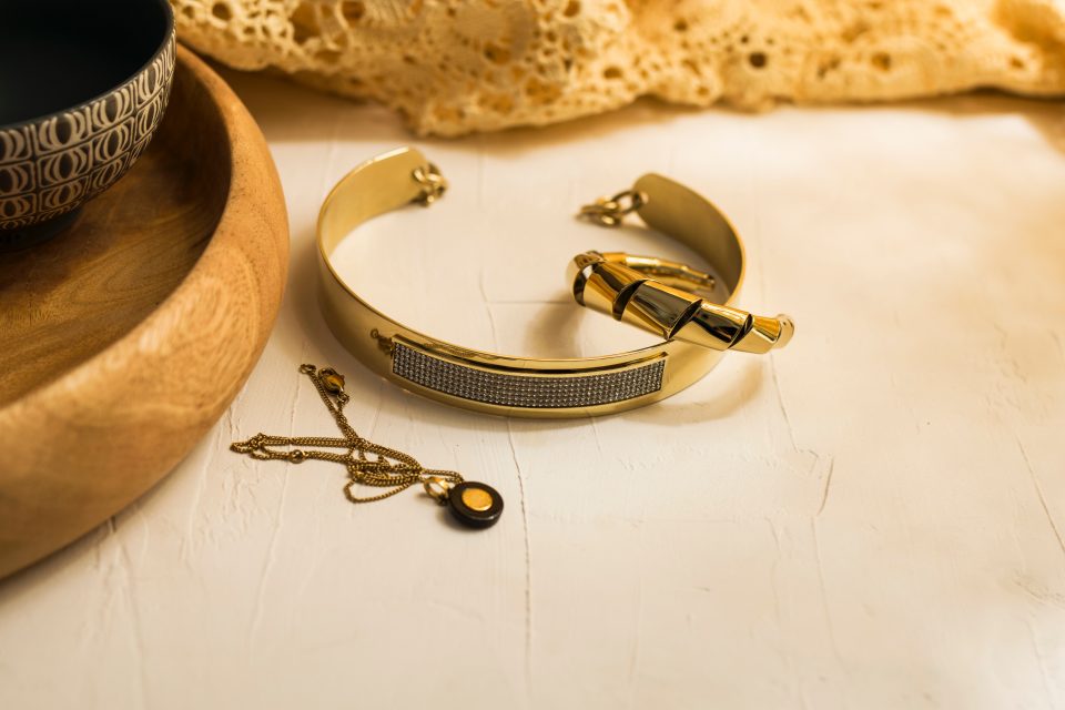 Stacked pieces of yellow gold jewelry on beige countertop.