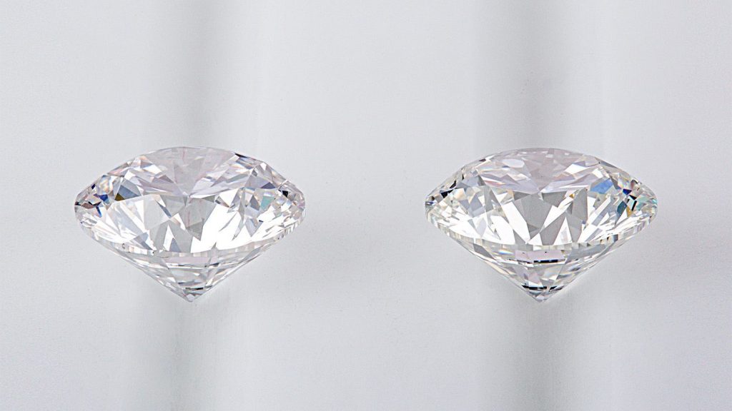 Two round cut diamonds on white table.