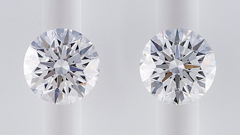 Two round cut diamonds on white table.