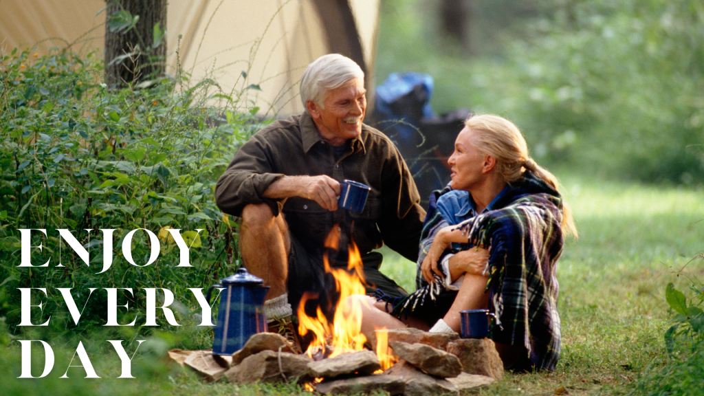 Older couple in front of campfire with text “Enjoy Every Day”.