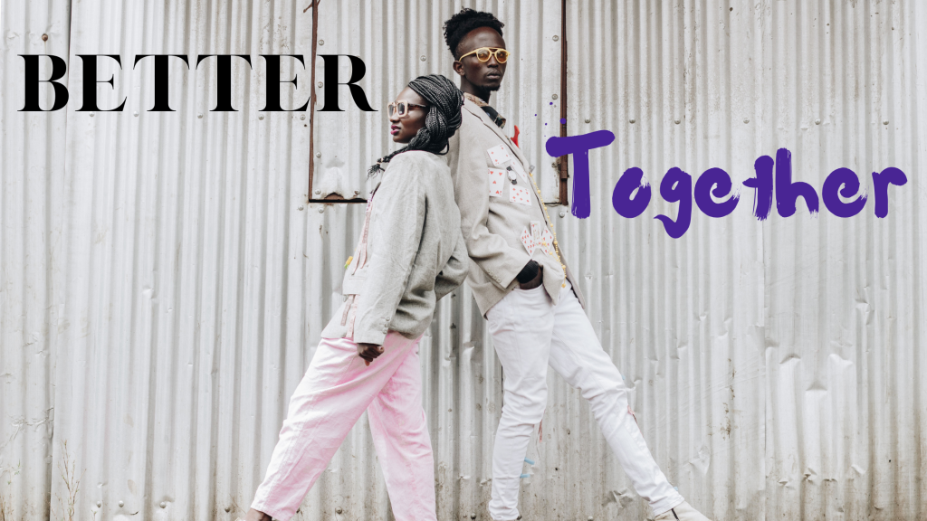 Two people leaning against each other in front of industrial white building with text “Better Together”.