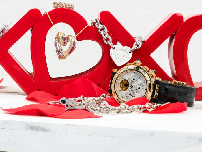 Various heart-themed jewelry pieces stacked around and on red “XOXO” statue.