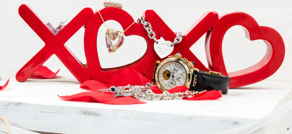 Various heart-themed jewelry pieces stacked around and on red “XOXO” statue.