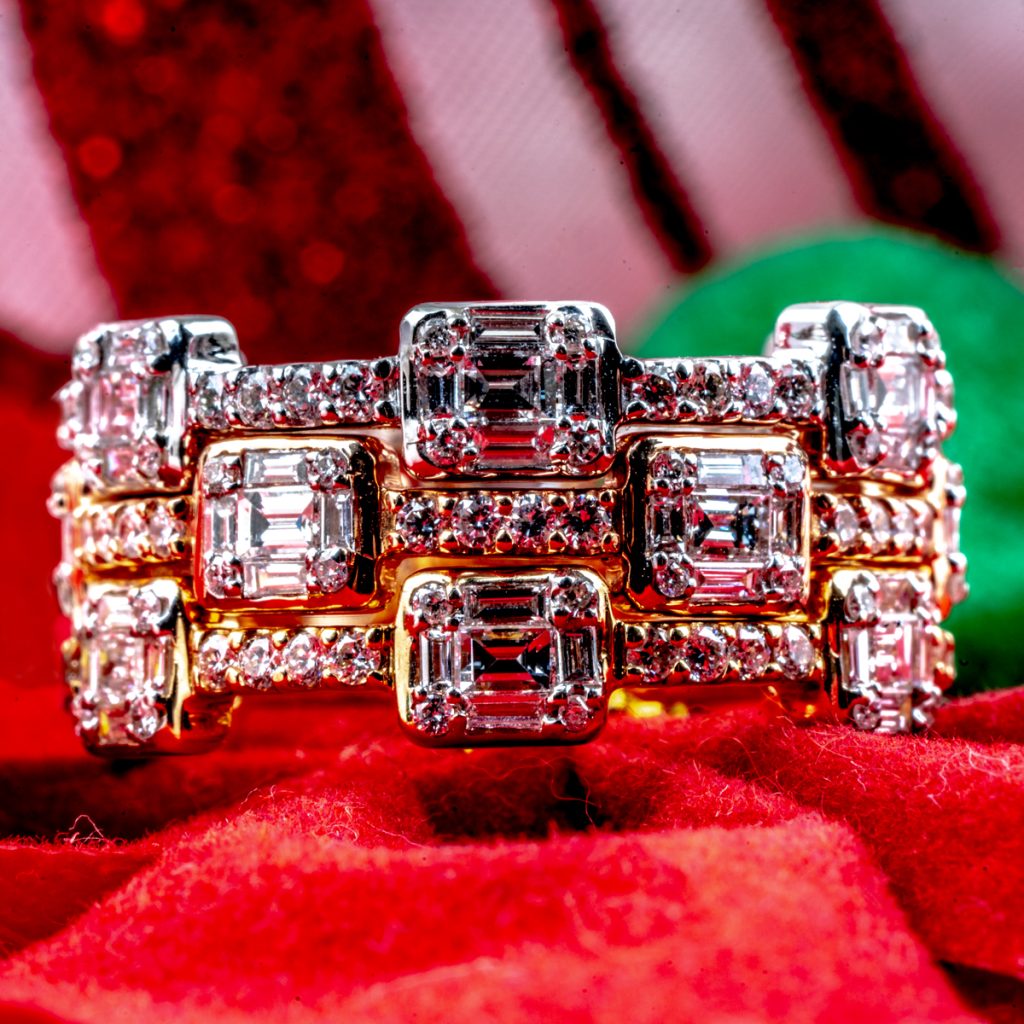 New white, rose, and yellow gold interlocking diamond rings on a red cloth background.