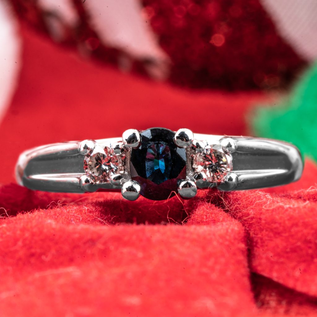 Vintage diamond and blue sapphire ring on a red cloth background.