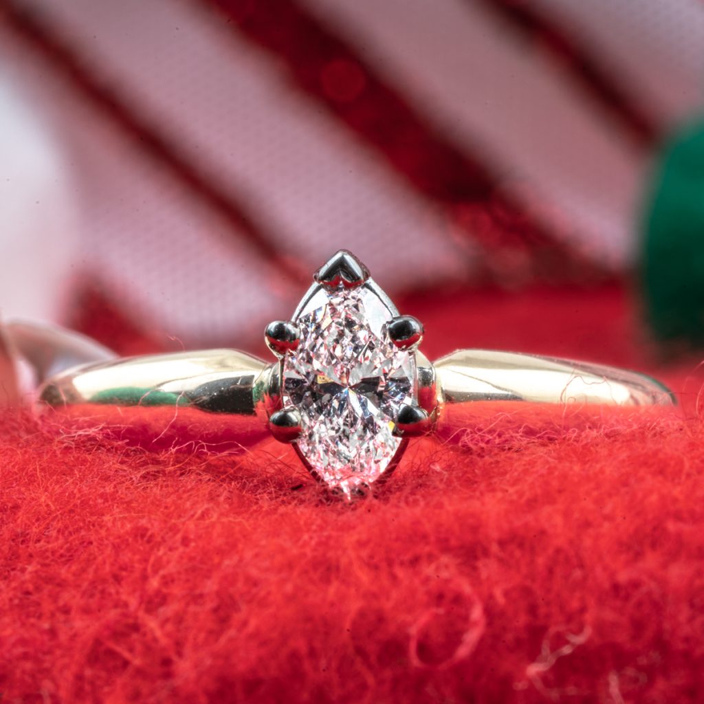 Vintage yellow gold solitaire diamond engagement ring on a red cloth background.