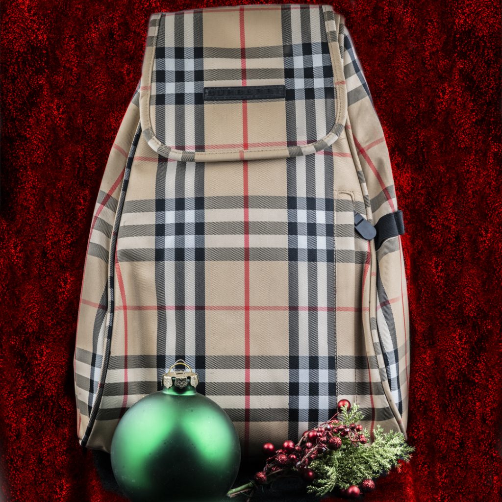 Vintage Burberry Nova Check golf shoe backpack on a red cloth background with mistletoe and a green ball ornament.