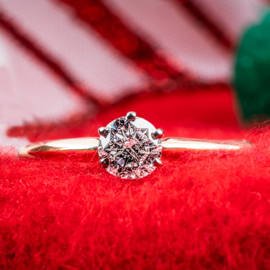 Vintage yellow gold solitaire diamond engagement ring on a red cloth background.