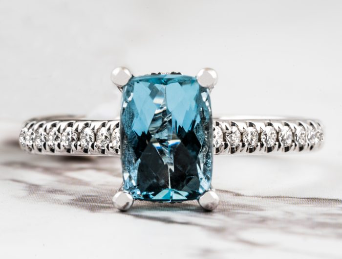 White gold engagement ring centered with an aquamarine and diamonds in the band.