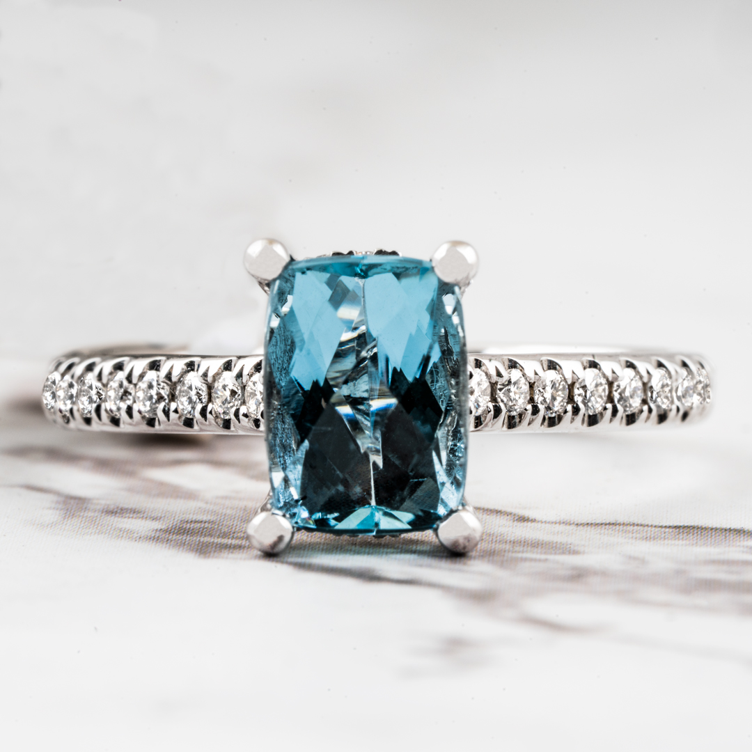 White gold engagement ring centered with an aquamarine and diamonds in the band.