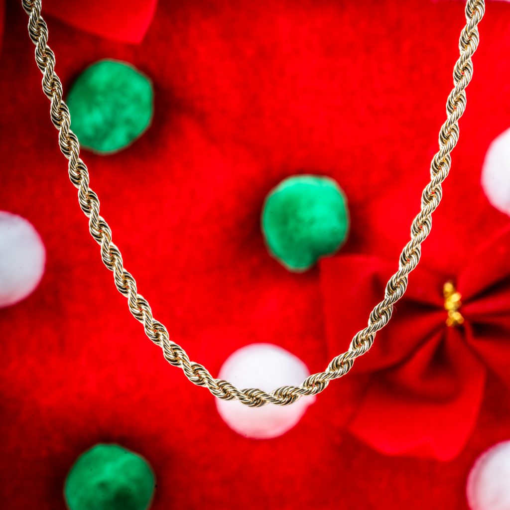 Vintage yellow gold rope chain on a red, green, and white cloth background.