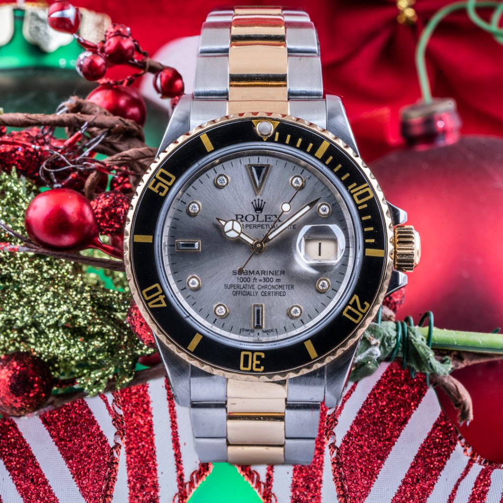 Pre-owned men’s Rolex Submariner 40mm on a mistletoe and red and white striped ribbon background.