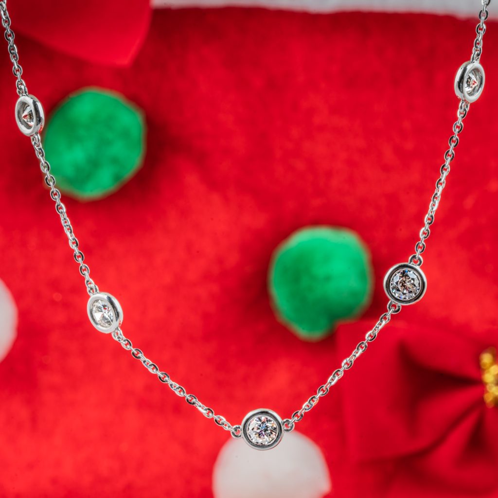 New lab-grown diamond station necklace on a red, green, and white cloth background.