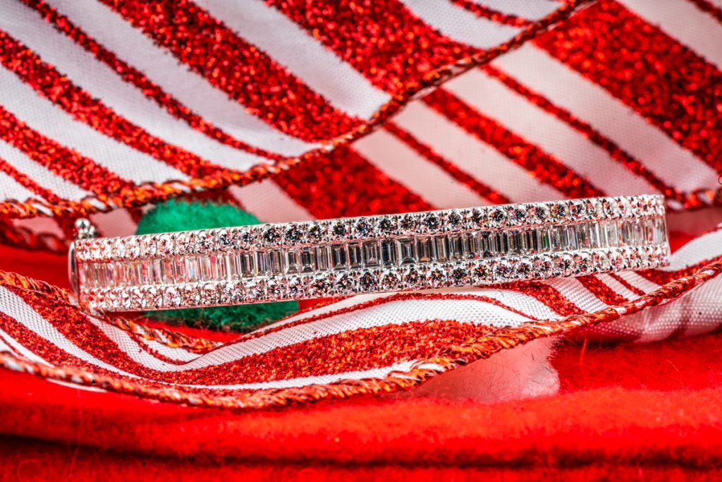 New white gold diamond tennis bracelet on a red and white striped ribbon background.