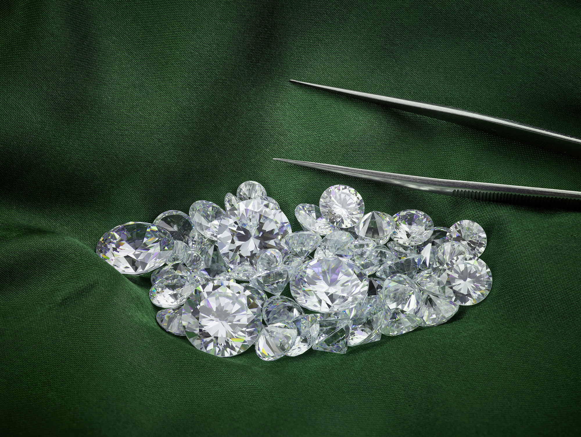 Small pile of loose cut diamonds sit next to tweezers on a green background.