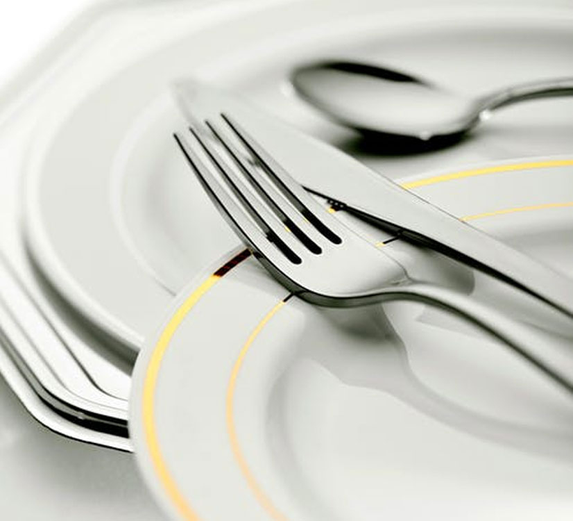 Silver flatware on top of white dinnerware.