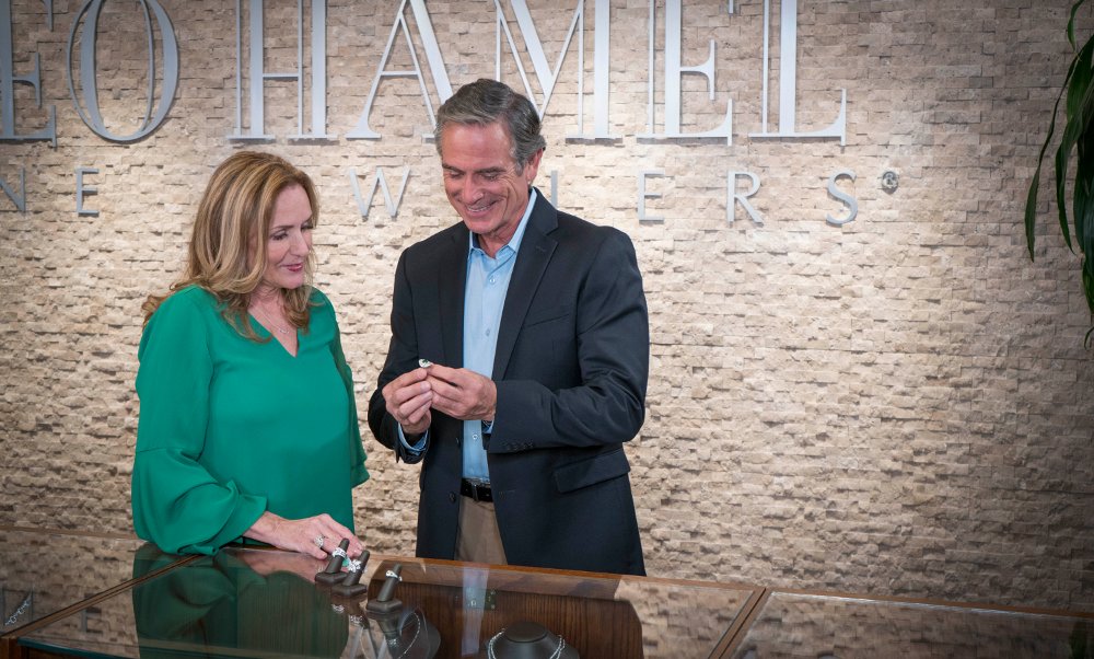 Lisa Hamel helping a middle-aged man pick out an engagement ring in the Leo Hamel Fine Jewelers showroom.