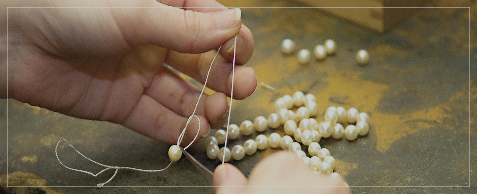 Person restringing pearls on a necklace