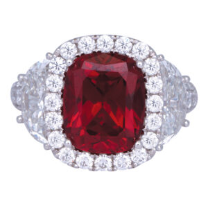 white gold engagement ring centered with a large cushion ruby surrounded by a diamond halo and flanked by diamonds